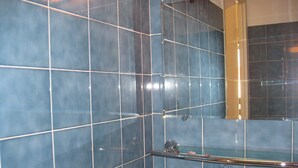 A bathroom with blue tiles, a glass shower enclosure, and a mirror. - T2 mezzanine near beach and shops (Saint-Cyprien)