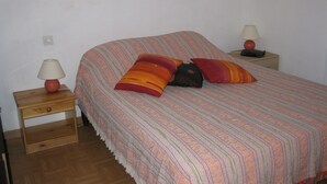 A single bed with a striped bedspread, two bedside tables with lamps, and a power outlet on the wall. - T2 mezzanine near beach and shops (Saint-Cyprien)
