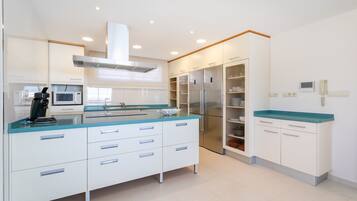 Una cocina moderna con armarios blancos, una encimera azul y un refrigerador de acero inoxidable.