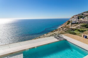 Una piscina con vista sul mare e su una collina con edifici.