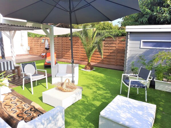 A backyard with a patio area featuring a swing chair, a cushioned bench, and a table with a woven basket. - Very nice villa 12p (6 bedrooms/6 bathrooms) seaside wifi air conditioning terrace garden (Borgo)