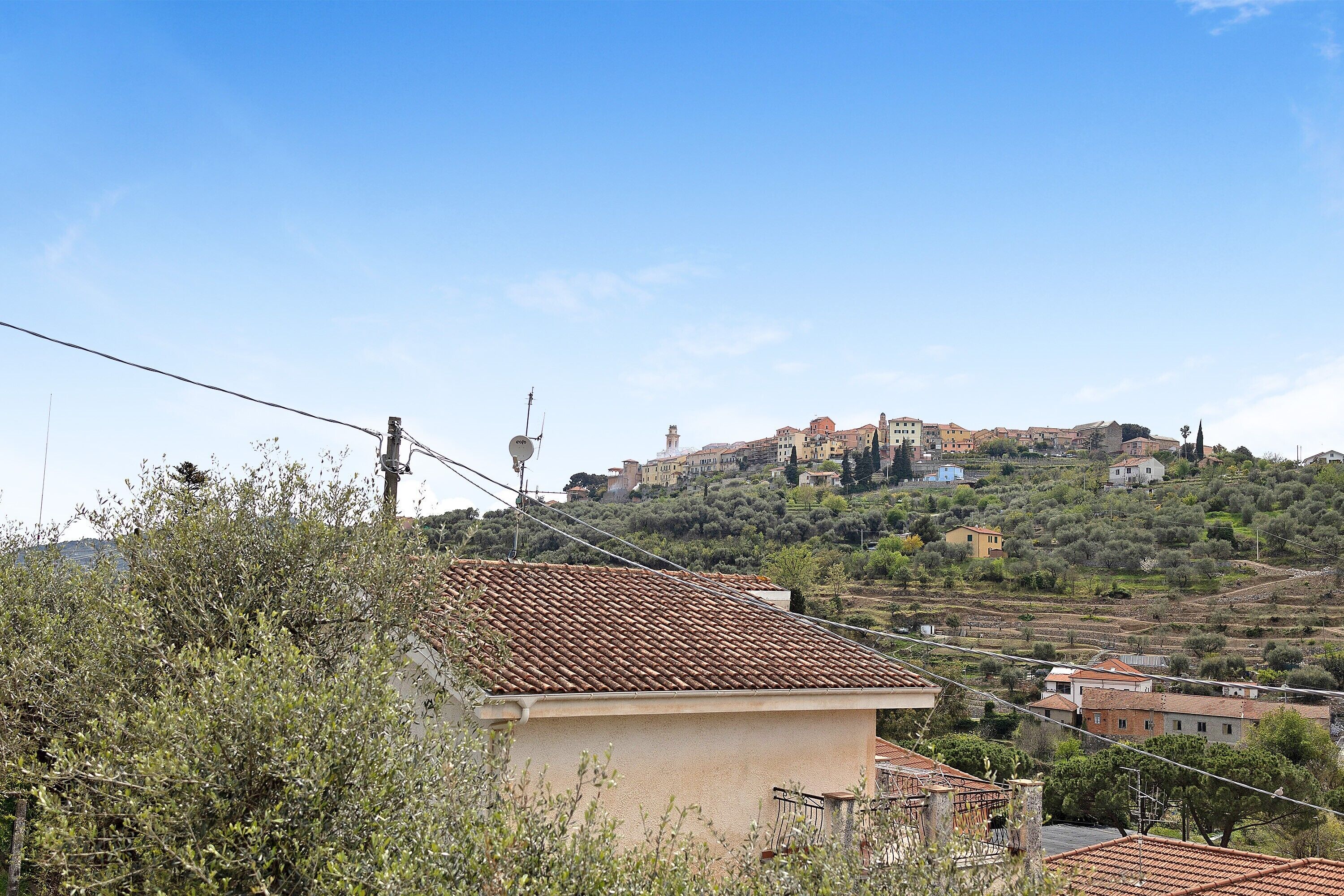 A hillside town with buildings, power lines, and vegetation.