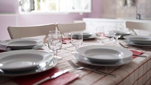 Une table à manger dressée avec des assiettes, des verres et des couverts, avec une fenêtre en arrière-plan.