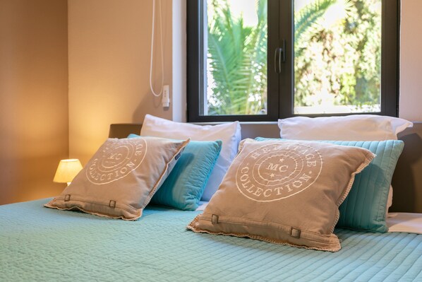 A bed with pillows, a window, and a lamp.