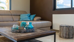 A living room with a sofa, a coffee table with decorative items, a clock on the wall, and a window with a view.