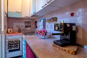 Una cocina con cafetera, estufa y lavaplatos.