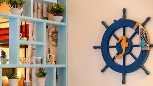 Un mur décoré sur le thème de la marine, une étagère bleu clair contenant divers objets et une petite plante en pot.