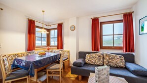 A room with a dining table, chairs, a sofa, a window with curtains, and a clock on the wall. - Apartment "Rieglhof Maisel" with Mountain View, Garden & Wi-Fi (Graun im Vinschgau)