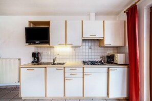 Cocina compacta con TV integrado, estufa a gas, microondas y cafetera.