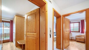 A room with wooden doors, a bench, a small table, and a view of the outdoors. - Apartment "Rieglhof Maisel" with Mountain View, Garden & Wi-Fi (Graun im Vinschgau)