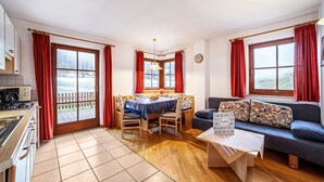 A room with a dining table, chairs, a sofa, a coffee table, and a kitchen area. - Apartment "Rieglhof Maisel" with Mountain View, Garden & Wi-Fi (Graun im Vinschgau)
