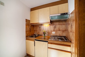 A kitchen with wooden cabinets, a stainless steel sink, a gas stove, and a built-in range hood.