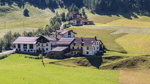 A large, multi-story building with a traditional architectural style, surrounded by green fields and trees.