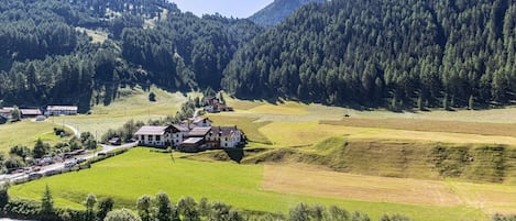 A rural landscape with a large house surrounded by fields, a river, and forested hills.