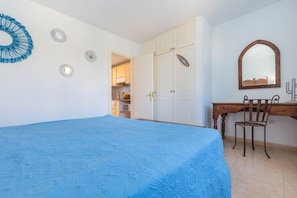 A bedroom with a bed, a desk, a chair, a wardrobe, and a mirror.