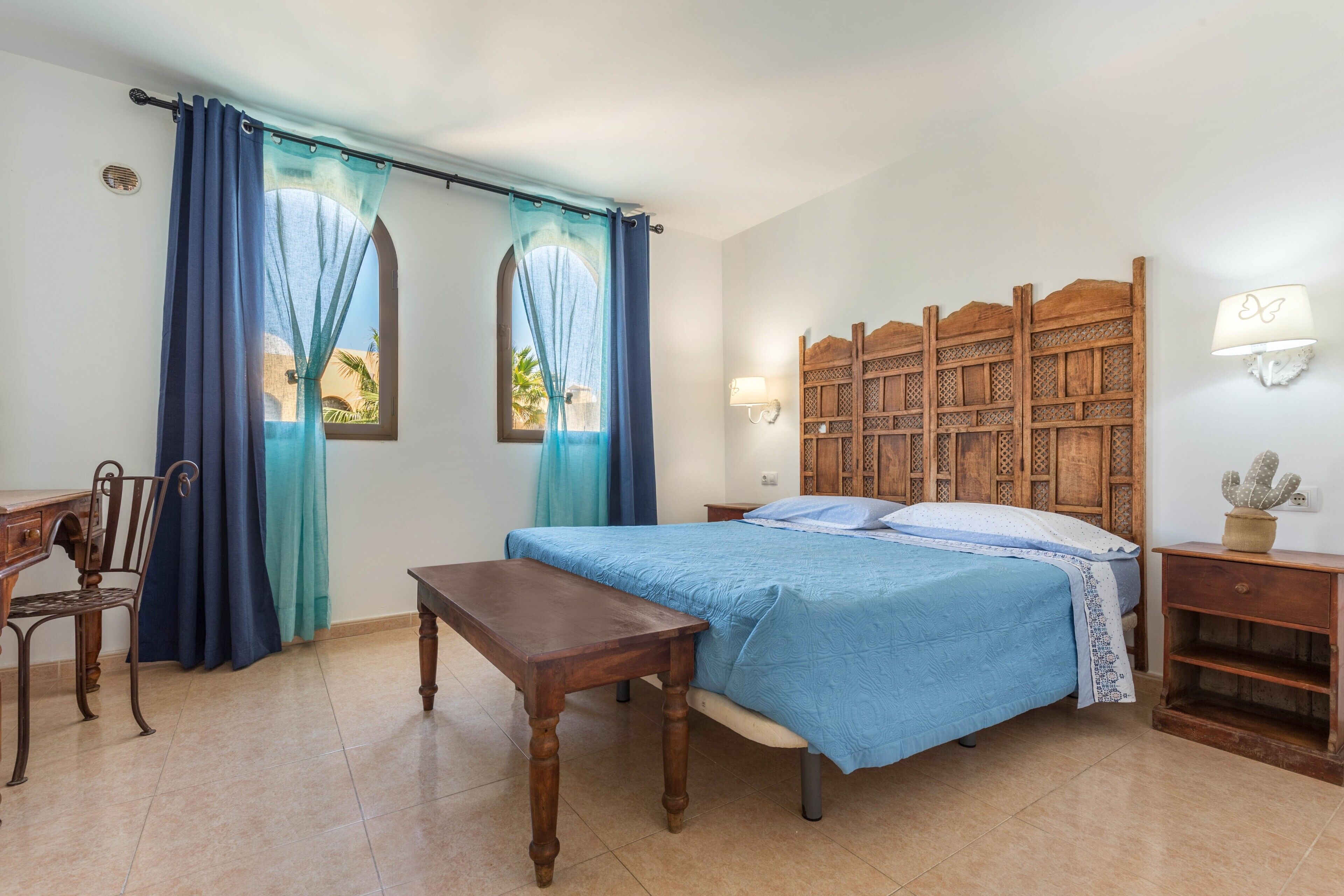 Une chambre à coucher avec un lit, une table de chevet en bois, un bureau et une chaise.