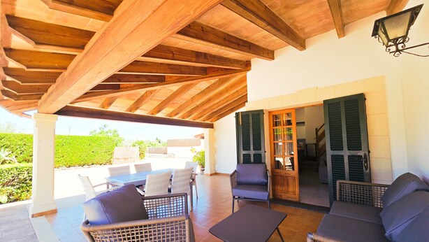 An outdoor patio with wicker furniture, a wooden ceiling, and a view of the garden. - Finca Villa Tranquila en Pollensa with Mountain View, Pool, Garden & Wi-Fi (pollensa)