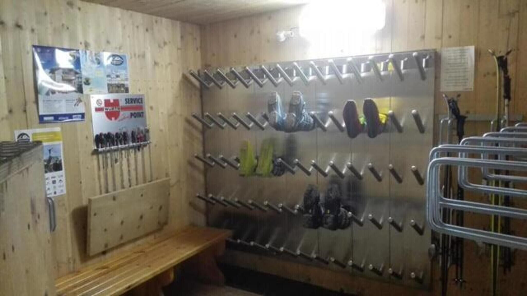 Een kamer met een houten wand, een bankje en een schoenenrek.