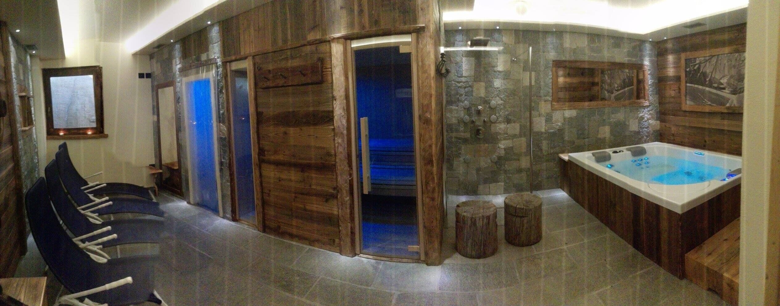 Un'area benessere con vasca idromassaggio, pareti in legno e una parete in pietra.