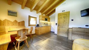 Een houten interieur met een eethoek, keuken en een aan de muur bevestigde televisie.