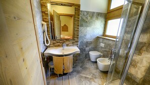 Een badkamer met een stenen muur, een wastafel, toilet en douche.