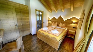 A wooden room with a bed, a wooden wardrobe, and a wooden bench.