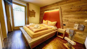 A wooden bed with a headboard, a bedside table, and a window with curtains. - Flat Mont dala Nef - Baita Cusini with Mountain View, Spa Area & Wi-Fi (Livigno)