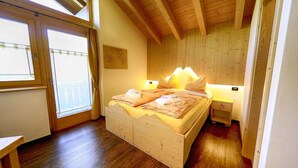 A bedroom with a wooden ceiling, a bed with pillows, a bedside table, and a window with curtains. - Flat Paradisin - Baita Cusini with mountain view, wellness area and Wi-Fi (Livigno)