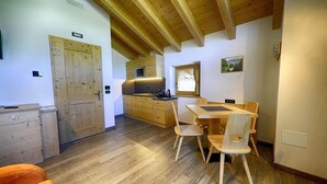 A wooden interior with a kitchen, dining area, and a door. - Flat Paradisin - Baita Cusini with mountain view, wellness area and Wi-Fi (Livigno)