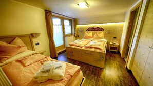 Ein Hotelzimmer mit zwei Betten, einem Kopfteil mit der Aufschrift 'Alpine Style', einem Nachttisch und einem Fenster mit Vorhängen.