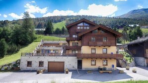 Un chalet à plusieurs étages doté d’un balcon, d’un garage et d’un espace de stationnement.