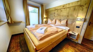 Un lit en bois avec une tête de lit, une table de chevet et une fenêtre avec des rideaux.