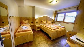 A wooden room with two beds, a small table, and a window.
