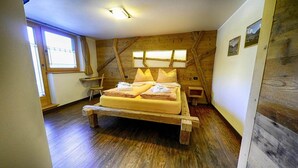Ein hölzerner Bettrahmen mit Kissen und Handtüchern, ein Fenster und ein Holzboden.
