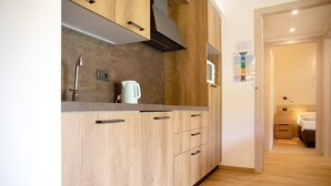 A modern kitchen with wooden cabinets, a stainless steel faucet, and a kettle.