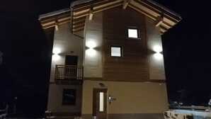 A two-story building with a balcony, a door, and a small window on the upper floor.