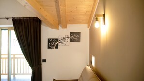 A room with a wooden ceiling, a sofa, a curtain, and wall-mounted light fixtures.