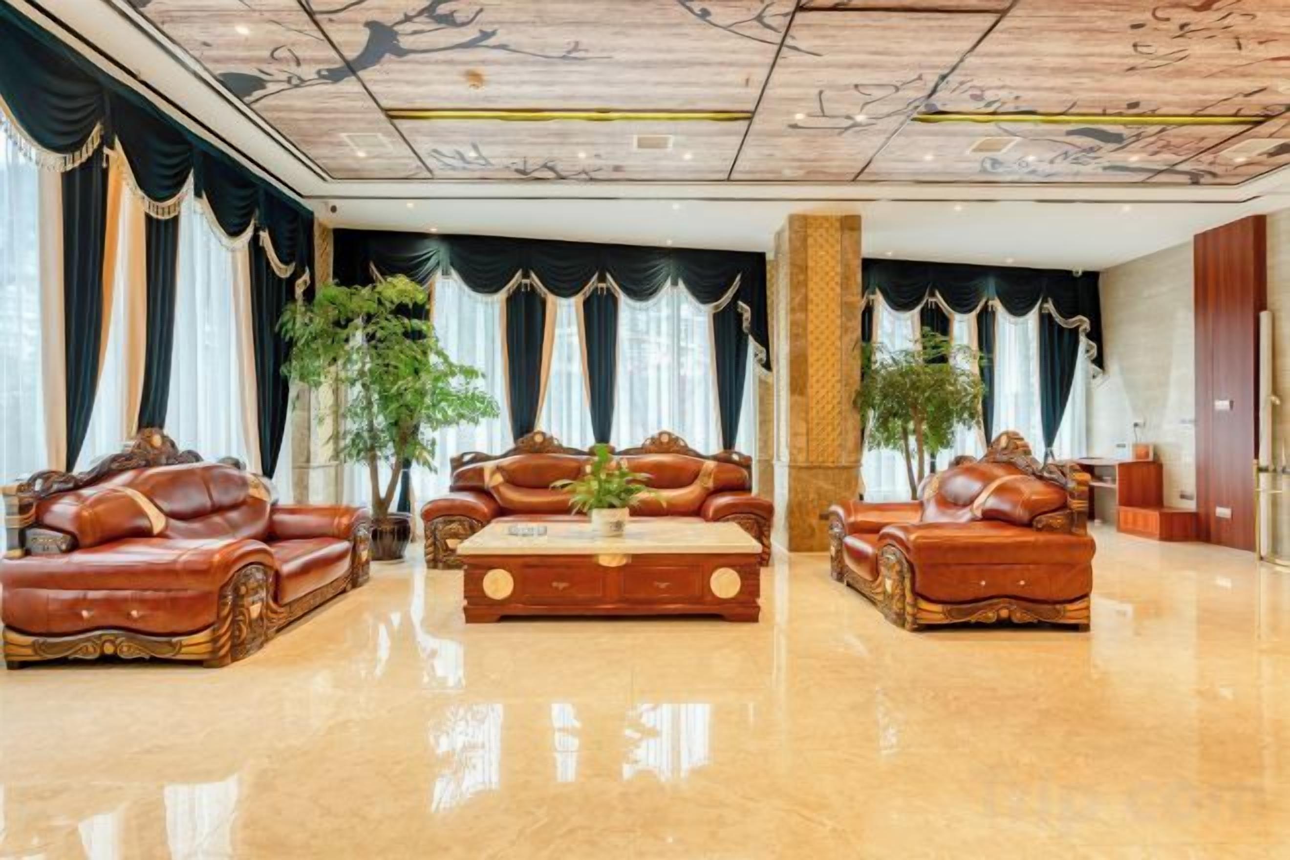 A spacious lobby with leather sofas, a coffee table, and large windows with curtains.