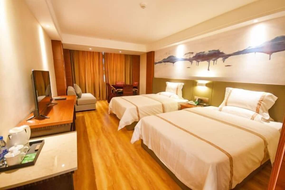 Ein Hotelzimmer mit zwei Betten, einem Schreibtisch mit Computer, einem Stuhl und einem Fernseher.
