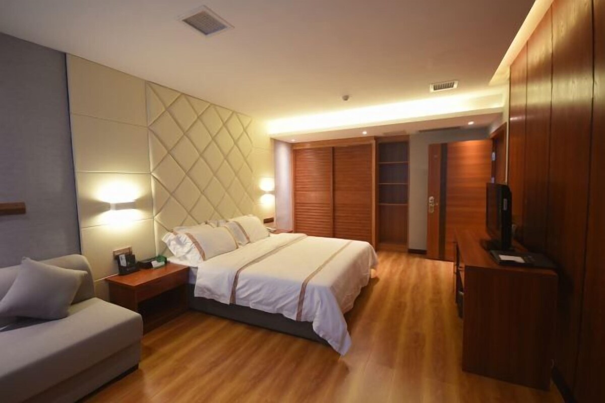 A hotel room with a bed, a bedside table, a TV, and a wardrobe.