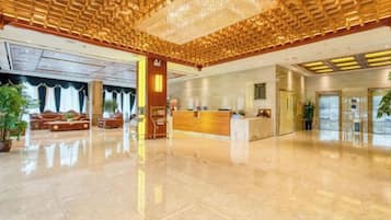 A spacious lobby with a reception desk, seating area, and a large chandelier.