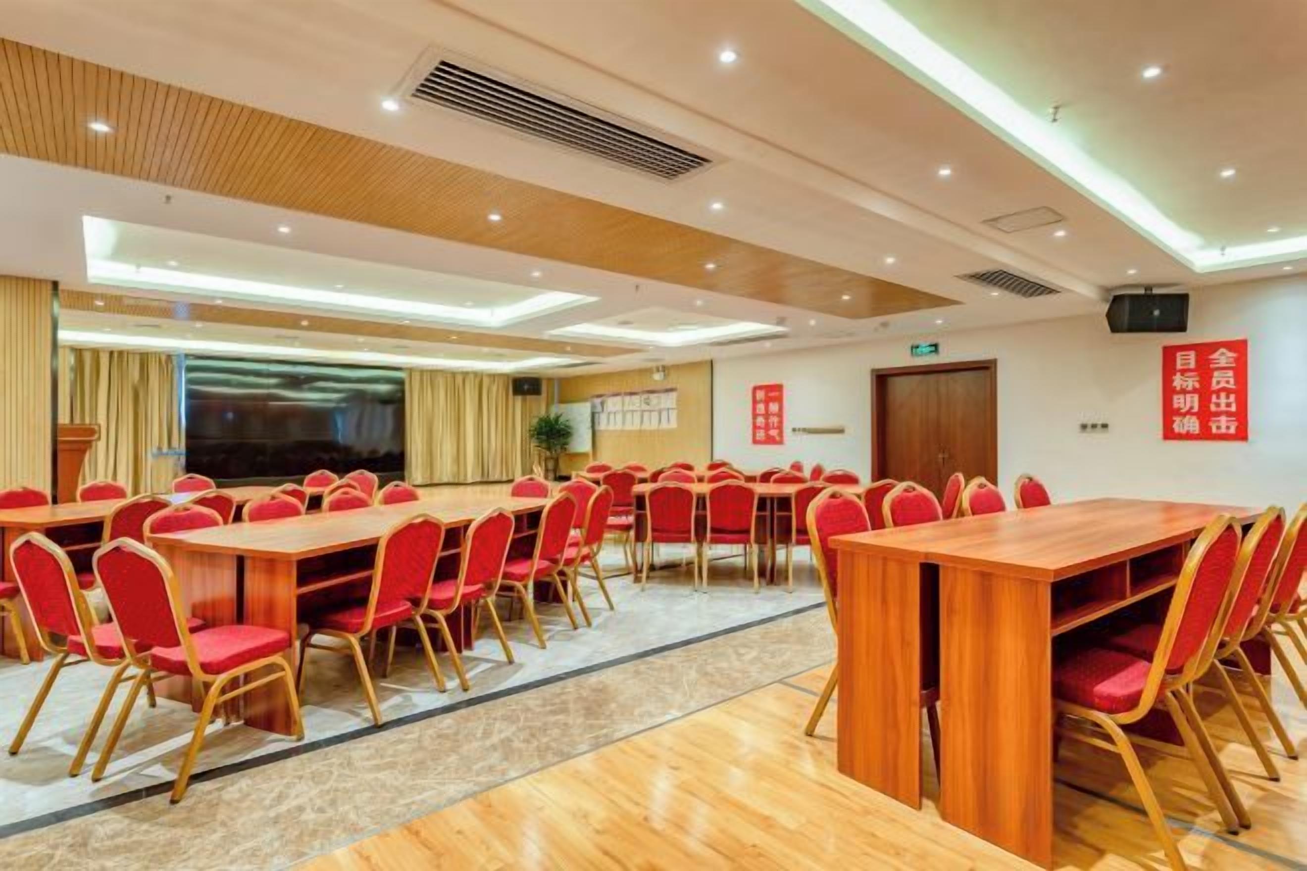 A conference room with multiple tables and chairs, a large screen, and a podium.