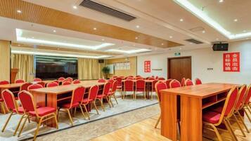 A conference room with multiple tables and chairs, a large screen, and a podium.