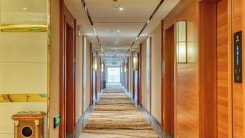 A hotel corridor with wooden doors, a patterned carpet, and a light fixture on the wall.