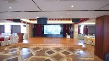 A spacious hall with a stage, seating arrangements, and a patterned floor.