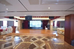 Een ruime zaal met een podium, zitplaatsen en een vloer met een patroon.