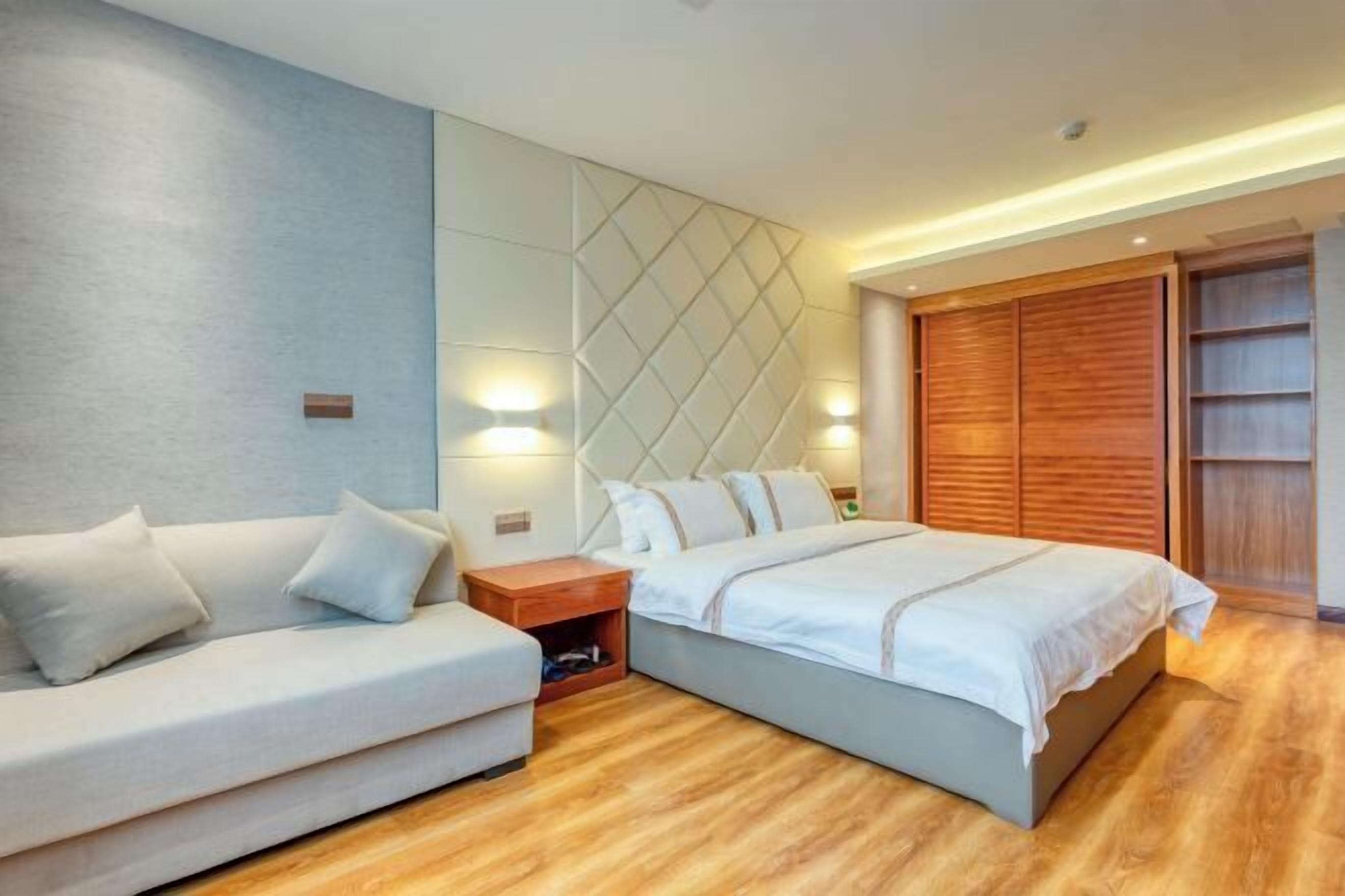 Ein modernes Schlafzimmer mit Bett, einer Couch, einem Nachttisch und einem Kleiderschrank.