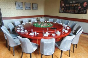 A conference room with a round table, chairs, and a floral centerpiece.