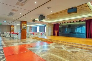 A hotel lobby with a stage, seating area, and a large window.