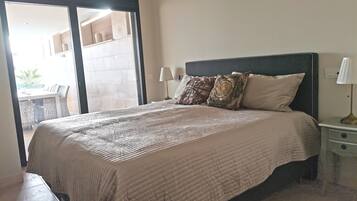 Un dormitorio con cama, mesita de noche, lámpara y vistas a un espacio exterior.